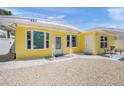 Close up of a bright yellow home with white trim, shell driveway, and small covered porch at 627 Avenida Del Norte, Sarasota, FL 34242