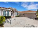 An exterior view of the home showcasing the terracotta roof, three-car garage and inviting driveway at 8102 Waterview Blvd, Lakewood Ranch, FL 34202