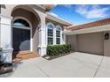 A close up of the front entrance featuring an arched doorway, updated gray front door, and manicured landscaping at 8102 Waterview Blvd, Lakewood Ranch, FL 34202