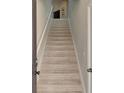 Carpeted staircase featuring a gray handrail and neutral walls leading to the upper level at 8417 Karpeal Dr # 4, Sarasota, FL 34238