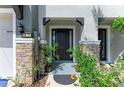 Stylish front entrance with stone accents, a black door, and lush landscaping at 8676 Ice Wine St, Sarasota, FL 34238