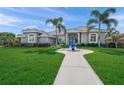 Charming home with lush green lawn, a decorative water feature, and a welcoming entrance at 8924 Misty Creek Dr, Sarasota, FL 34241