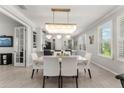 Elegant dining room with a modern chandelier, large windows, and beautiful flooring at 9012 Tequila Sunrise Dr, Sarasota, FL 34241