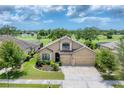 Charming tan house with a three-car garage, manicured lawn, and landscaping on a golf course at 9123 Raes Creek Pl, Palmetto, FL 34221