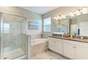 Bright bathroom features double vanity, a soaking tub and glass enclosed shower at 10609 Great Cormorant Dr, Riverview, FL 33579