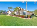 Landscaped front yard featuring mature palm trees and garden beds under a clear blue sky, enhancing curb appeal at 1144 Hoover St, Nokomis, FL 34275
