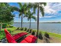 Relaxing backyard view with red lounge chairs and palm trees overlooking a serene lake at 138 Toscavilla Blvd, Nokomis, FL 34275
