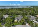 Stunning aerial view of a luxury home surrounded by lush landscaping and a bay in the distance at 140 Sugar Mill Dr, Osprey, FL 34229