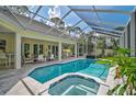 Screened-in pool and spa area with ample seating and a view of lush landscaping at 140 Sugar Mill Dr, Osprey, FL 34229