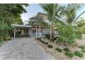 Charming two-story home with tropical landscaping, brick driveway, and covered parking at 160 Coolidge Dr, Sarasota, FL 34236