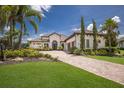 A beautiful single-story home featuring lush landscaping, a tile roof, and a paver driveway at 16531 Kendleshire Ter, Lakewood Ranch, FL 34202