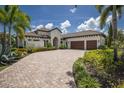 A beautiful single-story home featuring lush landscaping, a tile roof, and a paver driveway at 16531 Kendleshire Ter, Lakewood Ranch, FL 34202