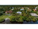 Waterfront home surrounded by mature tropical landscaping and lush greenery, with backyard access to the water at 2048 Larson St, Englewood, FL 34223