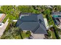 Aerial view of the single-story home featuring a black roof, screened pool, and lush backyard landscaping at 483 Partridge Cir, Sarasota, FL 34236