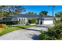 Beautifully landscaped single-story home with black roof, stone accents, a paved driveway, and a two-car garage at 483 Partridge Cir, Sarasota, FL 34236