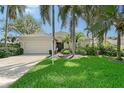Charming single-story home featuring a well-manicured lawn, a two-car garage, and vibrant landscaping with palm trees at 5839 Los Verdes Ct, Bradenton, FL 34210