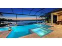 Stunning pool and spa area with a screened enclosure, offering a serene lake view and outdoor dining and lounge space at 7665 Haddington Cv, Lakewood Ranch, FL 34202