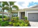 Inviting entryway with a decorative front door, side-entry garage access, and colorful landscaping at 8668 Sundance Loop, Sarasota, FL 34238