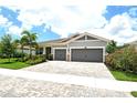 Well-maintained single-Gathering home featuring mature landscaping, a paver driveway, and a two-car garage at 8668 Sundance Loop, Sarasota, FL 34238