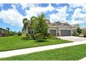 Beautiful home with a lush green lawn, mature trees, landscaping, and a paver driveway leading to the garage at 8668 Sundance Loop, Sarasota, FL 34238