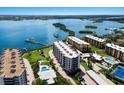 Scenic aerial view of waterfront condos, showcasing a swimming pool, tennis court, and boat docks at 8735 Midnight Pass Rd # 602B, Sarasota, FL 34242
