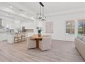 Bright dining area with a wooden table, modern lighting, and an open view to the kitchen and outdoor pool at 10120 Carnoustie Pl, Bradenton, FL 34211