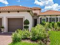 Elegant exterior view showcasing lush landscaping, a two-car garage, and a stylish terracotta-tiled roof at 10120 Carnoustie Pl, Bradenton, FL 34211