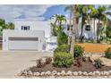 Well-maintained white home with palms and green landscaping, including driveway and attached garage at 1168 Westway Dr, Sarasota, FL 34236