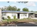 Street view of single-story home featuring a light exterior, carport, tidy landscaping, and mature trees at 1207 65Th Nw St, Bradenton, FL 34209