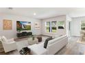 Modern living room with a large TV, stylish furniture, sleek floors, and natural light at 12071 Mountain Island Trl, Parrish, FL 34219