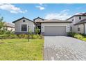Attractive home with a two-car garage, green lawn, and a brick-paved driveway, offering a welcoming curb appeal at 15127 Oxford Grey Dr, Bradenton, FL 34211