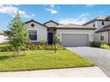 Inviting one-story home with a manicured lawn, decorative stonework, and a brick driveway leading to a two-car garage at 15127 Oxford Grey Dr, Bradenton, FL 34211