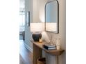 Hallway table featuring a lamp, candle, books, and decorative vase with a framed mirror above the table at 17737 Savory Mist Cir, Bradenton, FL 34211