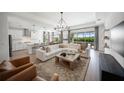 Open concept living room and kitchen with white sectional sofa, wooden coffee table, and kitchen island at 17737 Savory Mist Cir, Bradenton, FL 34211