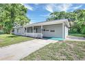 Side view of a single-story home with a covered porch, a lush lawn and mature trees under a bright sky at 2622 11Th W Ave, Bradenton, FL 34205