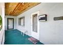 Covered front porch with a wooden ceiling, front door, mailbox, and a welcome mat, creating a cozy entry at 2622 11Th W Ave, Bradenton, FL 34205