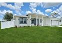 Modern home showcasing a well-maintained lawn, gray trim, and a white perimeter fence at 2794 Escambia Cir, North Port, FL 34288