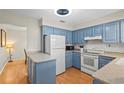 Cozy kitchen with blue cabinets, white appliances, a breakfast bar and laminate flooring at 409 Archibald Ave, Sarasota, FL 34243