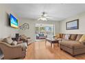 Bright living room with wood floors, a ceiling fan, and sliding glass doors to the screened-in porch at 409 Archibald Ave, Sarasota, FL 34243