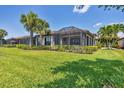 Expansive backyard with lush green lawn, mature landscaping, and screened lanai at 5863 Cavano Dr, Sarasota, FL 34231