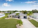 Inviting single-story home with green grass, palm trees and a long driveway leading to the front garage at 6178 Coliseum Blvd, Port Charlotte, FL 33981