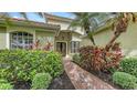 Charming front entrance featuring a brick walkway and lush tropical landscaping at 7012 Treymore Ct, Sarasota, FL 34243