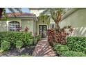 Charming front entrance featuring a brick walkway and lush tropical landscaping at 7012 Treymore Ct, Sarasota, FL 34243