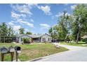 Single-story home featuring manicured lawn, mature trees and a long driveway at 9007 63Rd Avenue E Dr, Bradenton, FL 34202