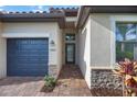 Elegant entrance with brick pavers, a glass-paneled front door, and stone accents enhancing curb appeal at 13422 Saw Palm Creek Trl, Lakewood Ranch, FL 34211