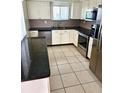 Updated kitchen with stainless steel appliances, granite countertops, white cabinets, and tile floors at 1604 Chevy Chase Dr, Sun City Center, FL 33573