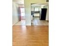 Open-concept living room with wood floors flows into a tile kitchen, featuring an entry with a red door at 1604 Chevy Chase Dr, Sun City Center, FL 33573
