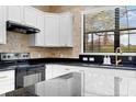Modern kitchen featuring white cabinets, granite countertops, stainless steel appliances, and a stylish backsplash at 19023 Mangieri St, Venice, FL 34293