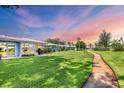 Expansive backyard featuring a lush green lawn, mature trees, and a walking path at 3721 Somerville Dr # 1513, Sarasota, FL 34232