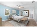 Comfortable bedroom with blue walls, ceiling fan, tile floor, and a large mirror that enhances the room's spacious feel at 3915 Meadow Creek Dr, Sarasota, FL 34233